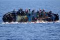 People jump off a boat moments before it overturns off the Libyan coast, in May.