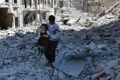 A photo from the anti-government Aleppo Media Centre shows a Syrian man holding a girl as he stands on houses destroyed ...