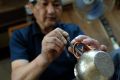 An artisan attaches a handle onto a copper teapot at Gyokusendo, a 200-year-old manufacturer of hand-hammered copperware ...