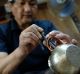 An artisan attaches a handle onto a copper teapot at Gyokusendo, a 200-year-old manufacturer of hand-hammered copperware ...