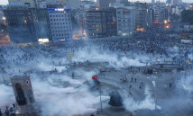 Protesters run as riot police fire teargas during a protest at Taksim Square