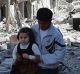 A photo from the anti-government Aleppo Media Centre shows a Syrian man holding a girl as he stands on houses destroyed ...