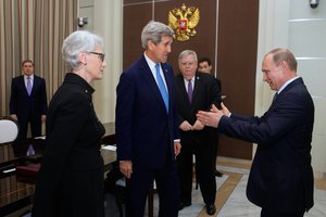 File - Russian President Vladimir Putin, watched by U.S. Secretary of State John Kerry, U.S. Under Secretary of State for Political Affairs Wendy Sherman, and U.S. Ambasador to Russia John Tefft, urges his guests to take their seat at the Bocherov Ruche - a government villa - in Sochi, Russia, before a bilateral meeting on May 12, 2015.