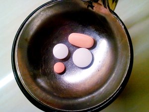 Pink and white tablets on a stainless steel saucer.