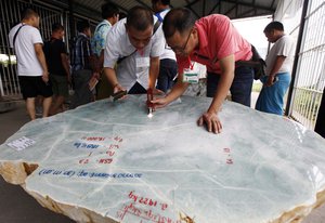 Gems merchants check a jade stone at the Gems Emporium in Naypyitaw, Myanmar, Friday, June 24, 2016.