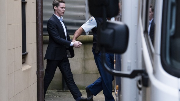 Oliver Curtis is led to a police van after being found guilty of insider trading.