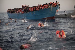 Migrants, most of them from Eritrea, jump into the water from a crowded wooden boat as they are helped by members of an NGO during a rescue operation at the Mediterranean sea, about 13 miles north of Sabratha, Libya, Monday, Aug. 29, 2016.