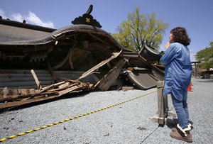 File: A woman prays in front of the historic Aso Shrine collapsed by powerful earthquakes in Aso, Kumamoto prefecture, Japan, Sunday, April 17, 2016.