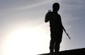 An Iraqi fighter belonging to a Sunni militia headed by Sheik Nazhan holds a rifle on the roof of Nazhan's home which ...