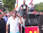 Demonstration, among the people a man with a microphone beside the vehicle with 