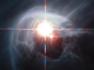 Two stars shine through the centre of a ring of cascading dust in this image taken by the NASA/ESA Hubble Space Telescope. The star system is named DI Cha, and while only two stars are apparent, it is actually a quadruple system containing two sets of binary stars. As this is a relatively young star system it is surrounded by dust. The young stars are moulding the dust into a wispy wrap. The host of this alluring interaction between dust and star is the Chamaeleon I dark cloud — one of three such clouds that comprise a large star-forming region known as the Chamaeleon Complex. DI Cha's juvenility is not remarkable within this region. In fact, the entire system is among not only the youngest but also the closest collections of newly formed stars to be found and so provides an ideal target for studies of star formation.