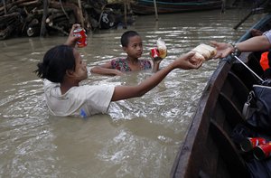 Flood victims standing in water receive foods from private donors near half-submerged residences in Nyaung Tone, Ayeyarwaddy Delta, about 60 miles southwest of Yangon, Myanmar, Friday, Aug 7, 2015.