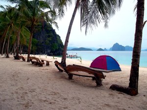 Wooden benches alternate with coconut trees facing the ocean and captivating view of El Nido, Palawan