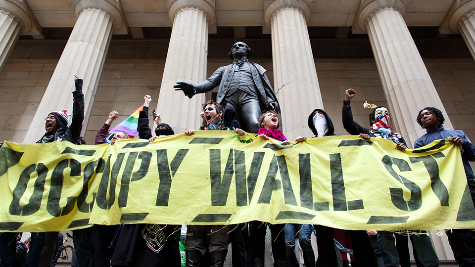 Occupy Wall Street demonstrators stand and cheer in front of the George Washington statue on Wall Street as they celebrate the protest's sixth month, Saturday, March 17, 2012, in New York. With the city's attention focused on the huge St. Patrick's Day Parade many blocks uptown, the Occupy rally at Zuccotti Park on Saturday drew a far smaller crowd than the demonstrations seen in the city when the movement was at its peak in the fall. A couple hundred people attended. (AP Photo/John Minchillo)