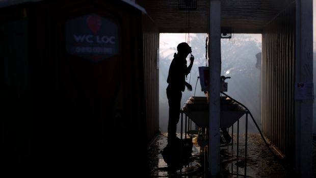 A migrant shaves amid the smoke from burning tents of the Jungle.