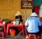 A woman selling Cau Lau, a local noodle specialty on a street sidewalk in Hoi An, Vietnam.