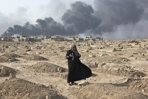 A woman prays over a grave of a family member at a graveyard damaged by Islamic State extremists in Qayara, some 31 miles, 50 km, south of Mosul, Iraq, Thursday, Oct. 27, 2016.