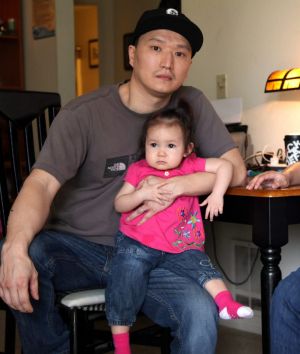 Adam Crapser, left, with daughters Christal, one, Christina, five, and his wife, Anh Nguyen, in the family's living room ...