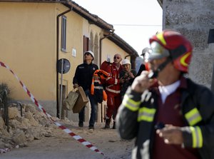 Italian firefighters escort a frightened woman just as an aftershock rattled Norcia, central Italy, after an earthquake with a preliminary magnitude of 6.6 struck central Italy, Sunday, Oct. 30, 2016.