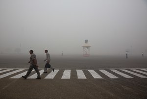 Indians walk to work as Delhi traffic police officers manage an intersection enveloped by smoke and smog, on the morning following Diwali festival in New Delhi, India