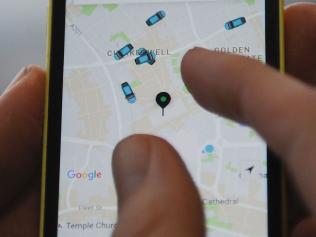 A man poses holding a smartphone showing the App for ride-sharing cab service Uber in London on October 28, 2016. Ride-sharing cab service Uber on October 28 lost a British tribunal case brought by drivers demanding basic workers' rights, in a decision that could affect thousands of workers. / AFP PHOTO / DANIEL SORABJI