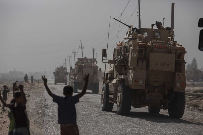 Child watch military vehicles pass into village, south of Mosul