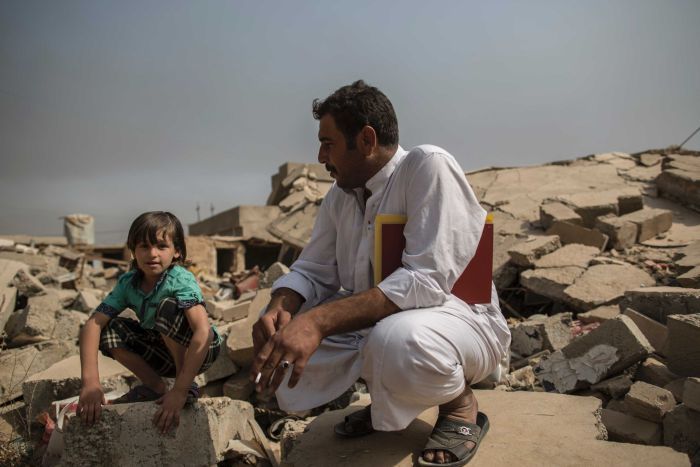 Mosul: father and son sit on the ruins of house in village of Imam Gharbi