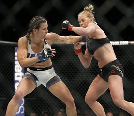 Miesha Tate, left, trades punches with Holly Holm during their UFC 196 women’s bantamweight mixed martial arts title match, Saturday, March 5, 2016, in Las Vegas. Tate won by fifth round submission.