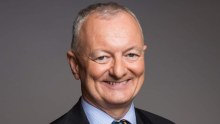 ABC election expert Antony Green smiles at the camera with his hands clasped behind his back.