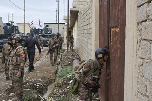 An Iraqi special forces soldier peeks through a hole in a door as his unit gets ready to search a compound in Gogjali, an eastern district of Mosul, Iraq, Wednesday, Nov. 2, 2016.