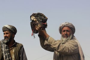 An Afghan man holds up the body of a child that was killed during clashes between Taliban and Afghan security forces in Kunduz province north of Kabul, Afghanistan, Thursday, Nov. 3, 2016, Authorities say a joint raid by U.S. and Afghan forces targeting senior Taliban commanders killed two American service members and 26 civilians.