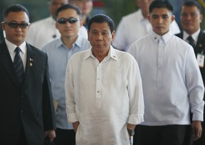 Philippine President Rodrigo Duterte, center,  is escorted to the podium for a news conference prior to boarding his flight for a three-day official visit to Japan at the Ninoy Aquino International Airport in suburban Pasay city south of Manila, Philippines Tuesday, Oct. 25, 2016.