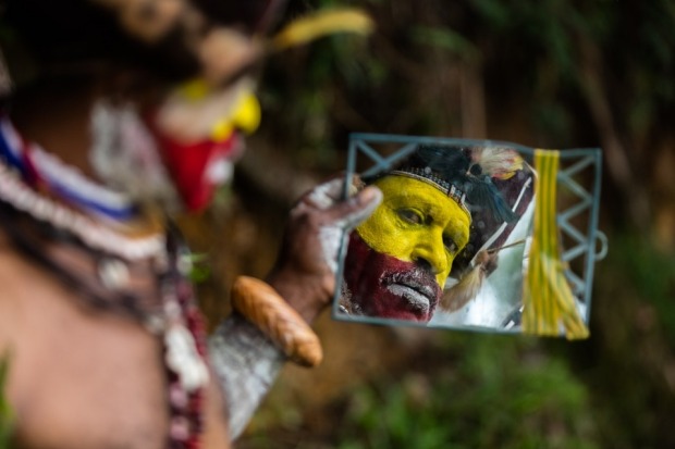 A mirror is essential to makeup preparation as this Huli wigman completes the final stages of dress and makeup for the ...