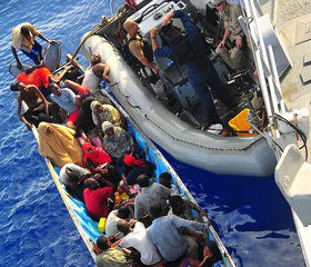 File - Somali migrants in a disabled skiff receive assistance from Sailors aboard the guided-missile cruiser USS Lake Champlain, Gulf of Aden.