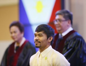 With the Philippine National flag in background, Filipino boxing great and now Senator Manny Pacquiao stands while a citation is being read to him during ceremony at the Commission on Elections Thursday, May 19, 2016 in suburban Pasay city south of Manila, Philippines.