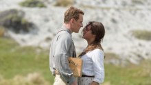 Michael Fassbender and Alicia Vikander stand outside, looking into each other's eyes.