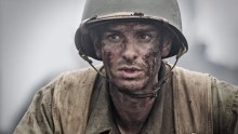 The mud-covered face of Andrew Garfield looks out from a trench in a scene from Hacksaw Ridge.