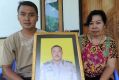 The widow of Wayan Sudarsa, Ketut Arsini, and her son Kadek Toni, hold a portrait of the police officer who was killed ...