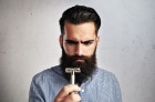 Portrait of brutal bearded man looking at vintage razor