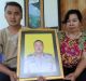 The widow of Wayan Sudarsa, Ketut Arsini, and her son Kadek Toni, hold a portrait of the police officer who was killed ...