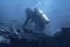 A scuba diver salvages scrap metal from a shipwreck.