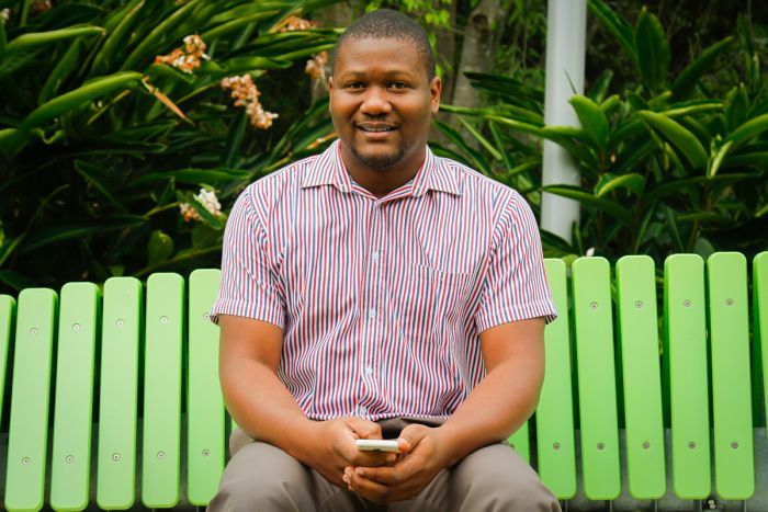 Marvin Reid holds his phone while sitting on a bench in Brisbane.