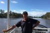 Man standing on houseboat with Murray River in the background.