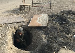 File - A soldier with Iraq's elite counterterrorism force inspects a tunnel made by Islamic State militants in Bartella, Iraq, Thursday, Oct. 27, 2016.