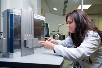 Scientist Nyssa Drinkwater at work in her laboratory wearing a white coat.