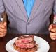 man holding a knife and a fork ready to eat a beef steak