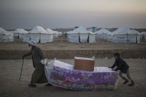 Iraqis displaced by fighting in Mosul carries mattresses at a camp for internally displaced people in Hassan Sham, Iraq, on Tuesday, Nov. 8, 2016.