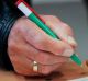 An MP uses a pen in the Hungarian national colours to vote against the government's proposed ban.