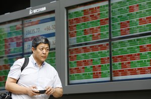 A man walks past an electronic stock indicator of a securities firm in Tokyo