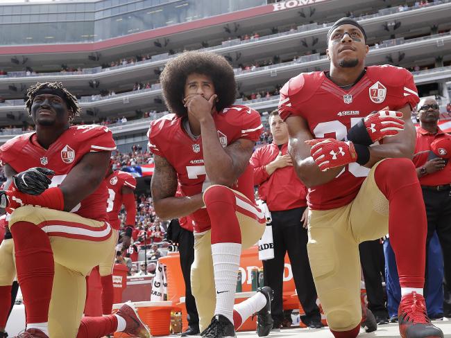 Kaepernick kneeling with teammates during the national anthem.